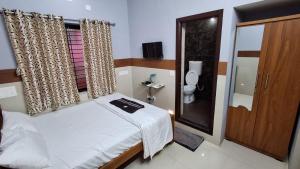 a small bedroom with a bed and a toilet at SJ Residency in Dharmastala