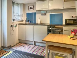 a kitchen with white cabinets and a wooden table at North Lakes Town House in Penrith