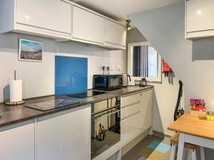 a kitchen with white cabinets and a microwave at North Lakes Town House in Penrith