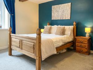a bedroom with a wooden bed and a blue wall at North Lakes Town House in Penrith
