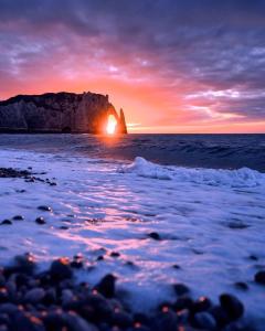 a sunset over the ocean with a rock formation at Le Clos des Souvenirs in Étretat