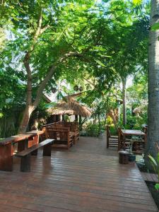 a wooden deck with benches and a straw umbrella at Wombat's B&B in Gili Trawangan