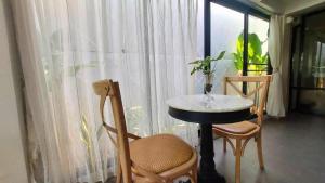 a table and chairs in a room with a window at Flow Garden Residence in Chiang Mai