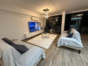 a living room with two beds and a flat screen tv at Villa Paradise BODRUM, 14 personnes, vue mer, piscine, plage privée, sauna, chambre à vapeur, ascenseur in Milas