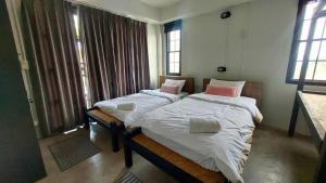two twin beds in a room with windows at Flow Garden Residence in Chiang Mai