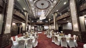 a banquet hall with white tables and chairs and a chandelier at Karam Al Balad Hotel in Jeddah