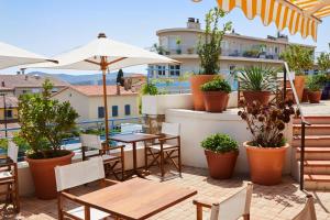 an outdoor patio with tables and chairs and potted plants at Hôtel California in Le Lavandou