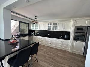 a kitchen with white cabinets and a black counter top at Villa Paradise BODRUM, 14 personnes, vue mer, piscine, plage privée, sauna, chambre à vapeur, ascenseur in Milas