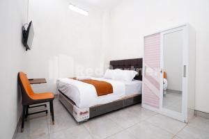 a bedroom with a bed and a desk and a mirror at Griya Poerwoto Syariah near Pasar Klewer Solo RedPartner in Solo