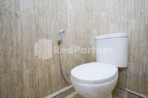 a white toilet in a bathroom with wooden walls at Griya Poerwoto Syariah near Pasar Klewer Solo RedPartner in Solo