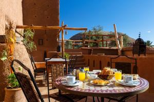 a table with food and drinks on a patio at Kasbah Tebi in Aït Benhaddou