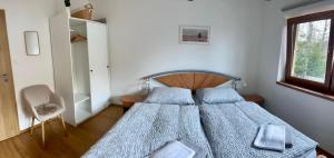 a bedroom with a bed and a chair and a window at Apartmán Blatka in Nová Pec