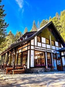 a large building with benches in front of it at Majláthova Chata Popradské Pleso in Vysoké Tatry