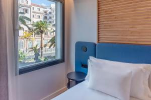 a bed with a blue headboard and a window at Barceló Santa Cruz Contemporáneo in Santa Cruz de Tenerife