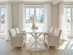 a white dining room with a white table and chairs at Techts Strandhaus in Timmendorfer Strand +66 photos