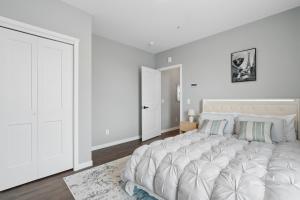 a white bedroom with a large bed and a door at Valclyde Elevated Urban Haven in Minneapolis