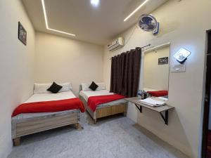 a small room with two beds and a mirror at Hotel Shivay Deluxe in Nagpur