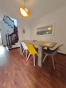 a dining room with a wooden table and yellow chairs at Eiras AL Ilha da Madeira in Santa Cruz