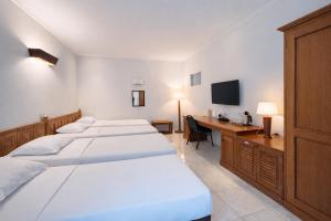a room with three beds and a desk and a computer at Hotel Winotosastro Garden in Yogyakarta