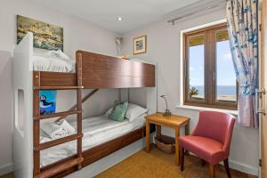 a bedroom with a bunk bed and a desk and a chair at House 43 in Looe