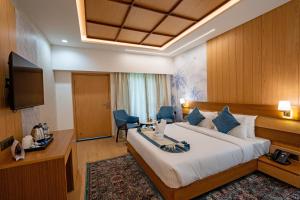 a hotel room with a bed and a desk and a television at Arkaya Mukteshwar by SuperGlitz Resorts Pvt Ltd in Mukteshwar