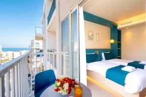 a hotel room with a balcony with a bed and flowers on a table at Atlantis Lodge in Marsalforn