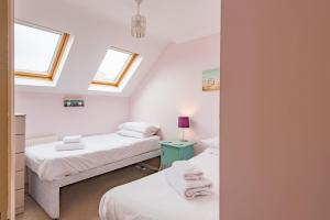 two beds in a room with two windows at Gerald's Place in Deal