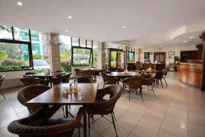 a restaurant with tables and chairs and windows at Hotel Winotosastro Garden in Yogyakarta