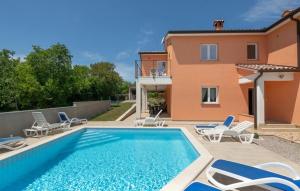 a swimming pool with chairs and a house at Villa Paola Vinez in Labin