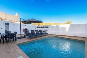 a swimming pool with chairs and a table and an umbrella at Dar Sara Holiday Home in Victoria