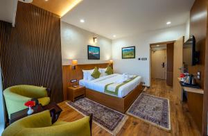 a hotel room with a bed and two chairs at Arkaya Mukteshwar by SuperGlitz Resorts Pvt Ltd in Mukteshwar