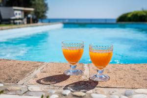 two glasses of beer sitting next to a swimming pool at Beachfront villa with direct access -Private pool & Zen Area in Quartu SantʼElena