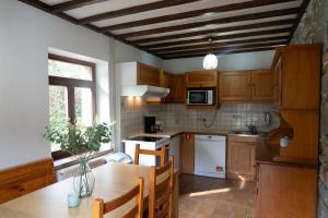 a kitchen with wooden cabinets and a table with chairs at Maison de la Turbine in Yvoir