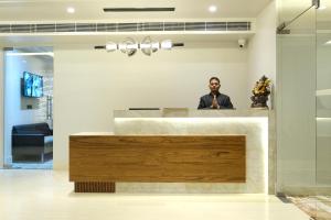 a man sitting at a counter in a room at Red Sapphire Royale in Morādābād