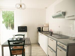 a white kitchen with a table and a table and chairs at LE REPOS DU VOYAGEUR T3 45 m2 tout confort in Lussac-les-Châteaux +16 photos