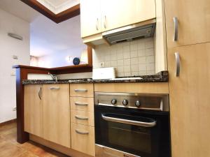 a kitchen with wooden cabinets and a black oven at AC Apartaments Cabirol Incles in Incles