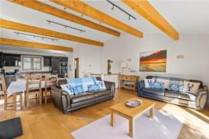 a living room with couches and a table and a kitchen at House 35 in Looe
