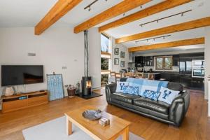 a living room with a black leather couch and a table at House 35 in Looe