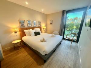 a bedroom with a large bed and a large window at Best Western Hotel de la plage Normandie in Asnelles