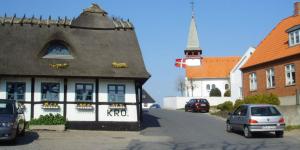 a building in a town with cars parked on the street at Reersø Kro in Reersø