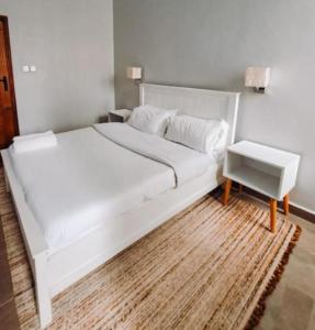 a bedroom with a white bed and a night stand at Chaka homes 2 bedroom in Kiganjo