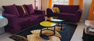a living room with a purple couch and a table at Chaka homes 2 bedroom in Kiganjo +1 photo