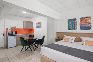 a bedroom with a bed and a table and a kitchen at Larnaca Bay Suites in Larnaca