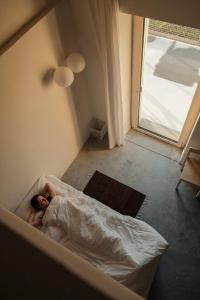 a person laying on a bed in a room with a window at Gabanon in Casale Monferrato
