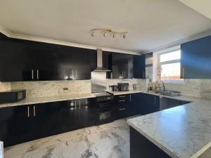 a kitchen with black cabinets and marble counter tops at Mountain Ash Cottage in Mountain Ash