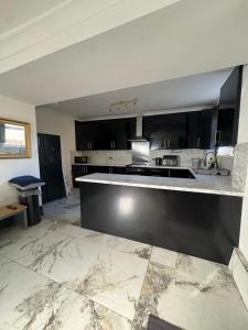 a kitchen with black cabinets and a marble floor at Mountain Ash Cottage in Mountain Ash +6 photos