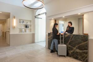 two women standing at a reception desk with a suitcase at Hotel Astoria Garden in Rome