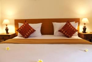 a large bed with two pillows and two lamps at Tara House in Ubud