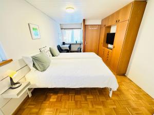 a bedroom with a large white bed and a chair at Studio Breiti I eigener Eingang l self check in l nähe Basel in Pratteln