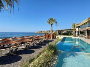 a swimming pool with chairs and umbrellas next to the ocean at Esentepe Collection Nothern Cyprus Villas & Apartments with Sea View Nothern Cyprus in Pallouriotissa